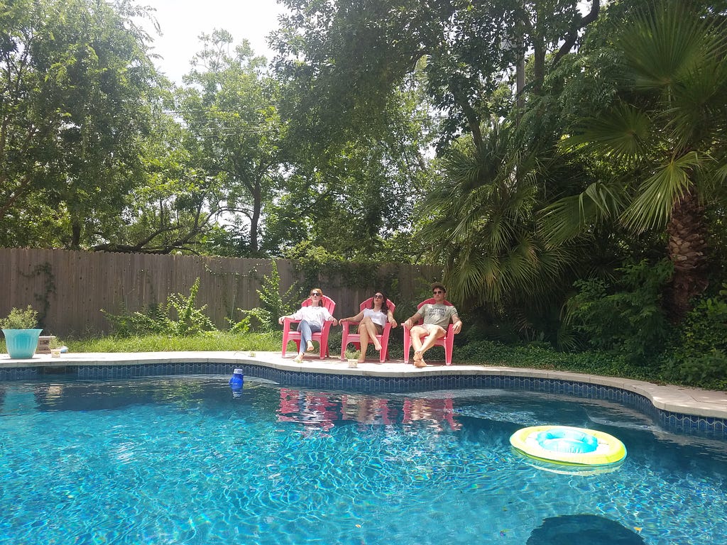Aubrey, Ann, and Rob relaxing on a sunny day in chairs by a pool