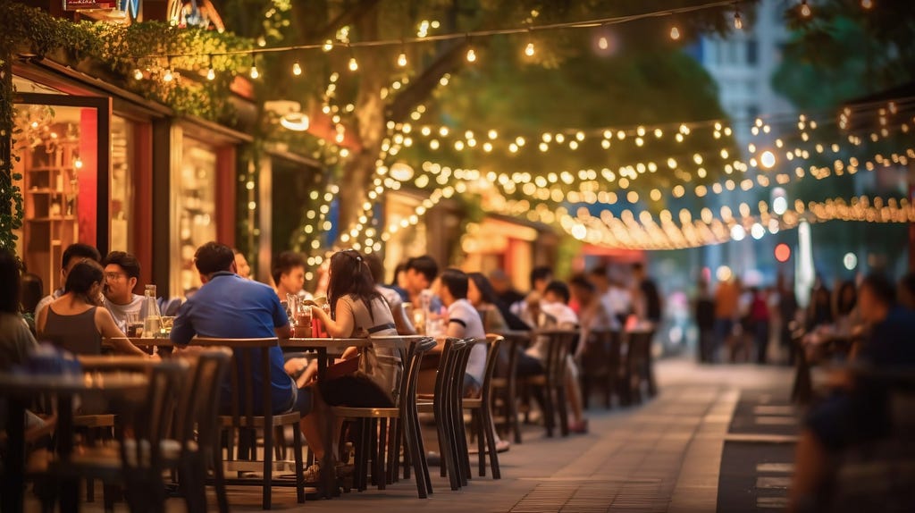 Outdoor restaurant seating on a walkway with overhead string lights