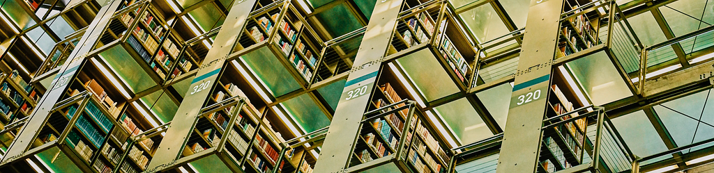 Imagem de uma grande biblioteca com estantes de ferro cheias de livros.