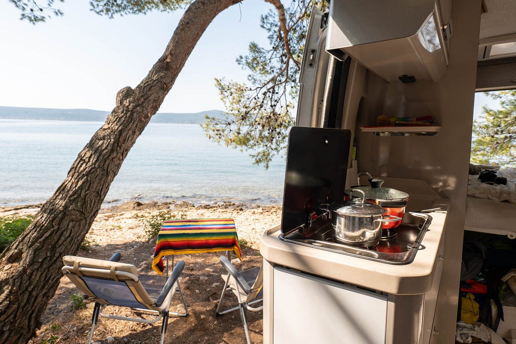 Beach viewed through the side door of a camper van