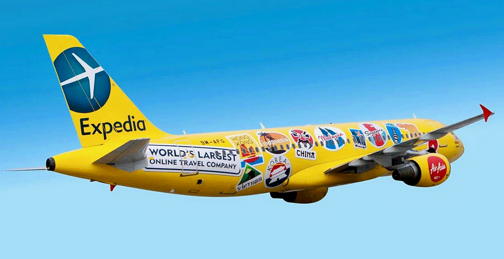 Yellow jet plane covered in travel stickers, flying through the sky