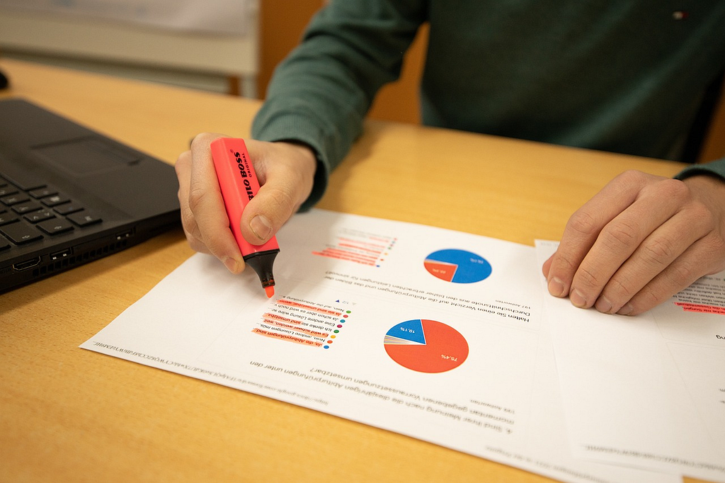 A Faceless Person Highlighting Text on a Data Analytics Printout Illustrating a Company’s Print Usage Patterns and Performance