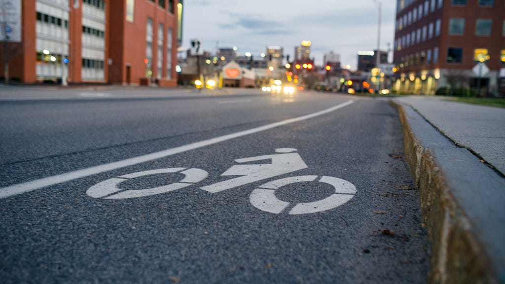 A close-up photo of the cyclist symbol on a bike lane on a street.