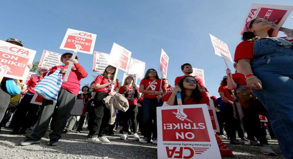 An image of people dressed in red shirts holding up red picket signs that say “CFA ON STRIKE!”