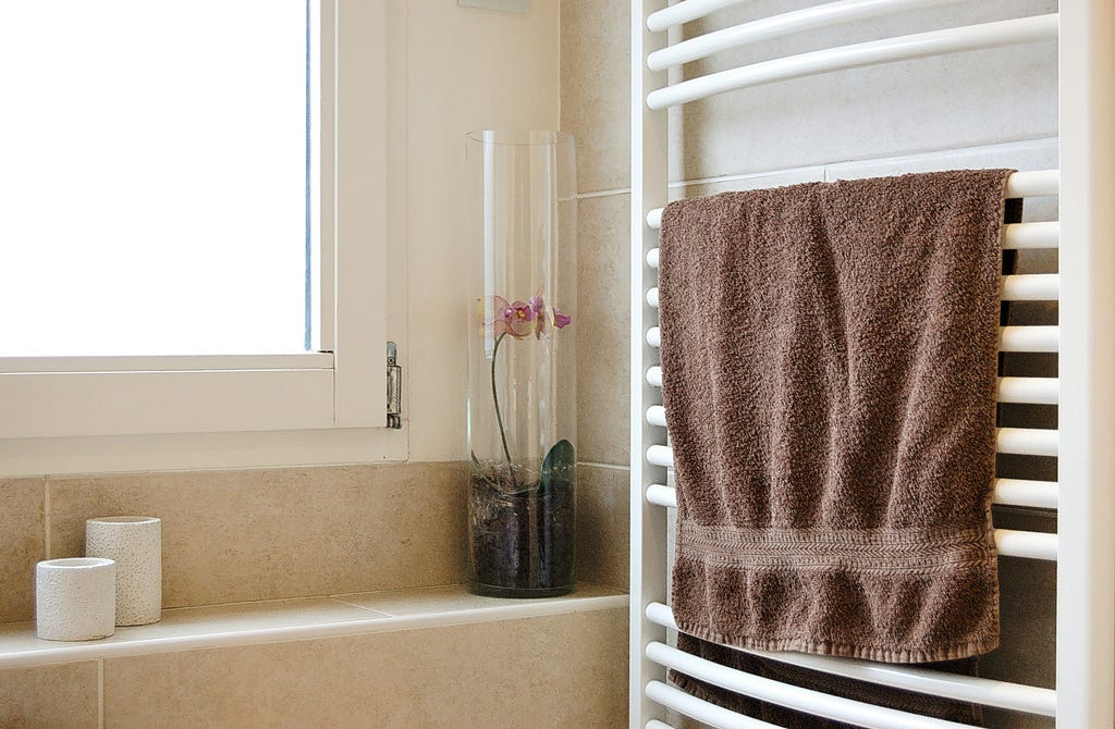 Bathroom interior, displaying a heating rack with a towel on it.