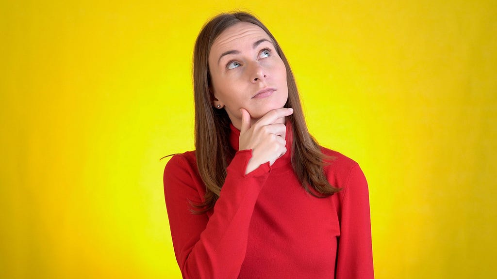 Young woman isolated on yellow background in studio looking curious.