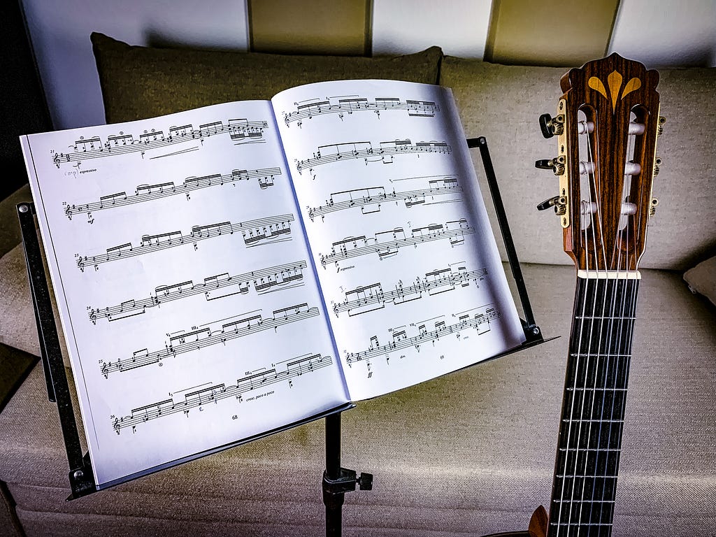 Sheet music on a music stand and a guitar