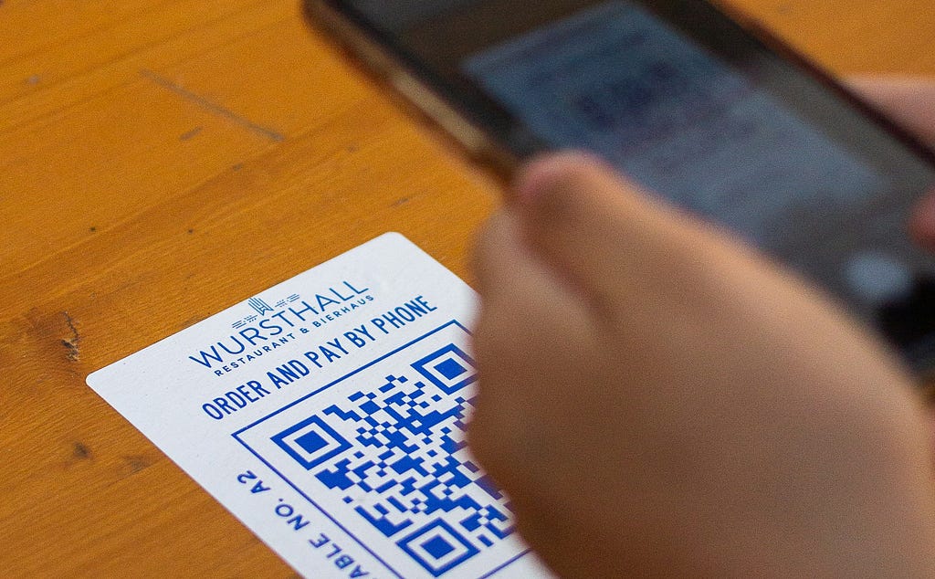 A smartphone scanning a QR code on a restaurant card for ordering and payment, showcasing seamless digital convenience.