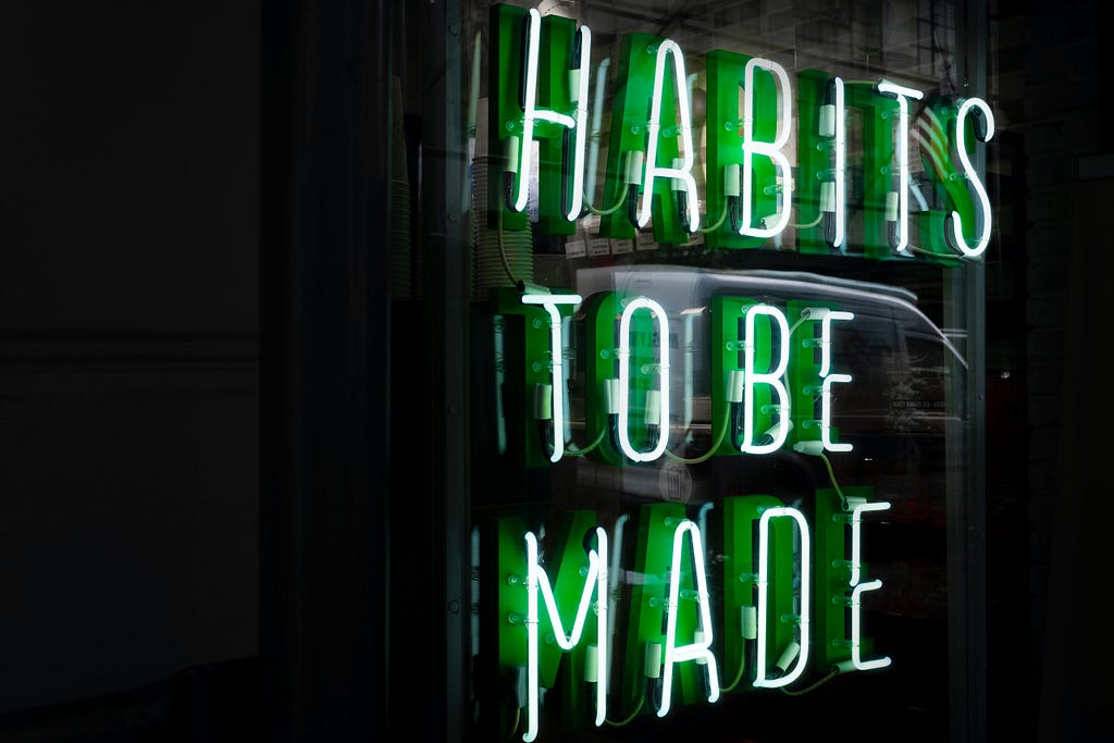 An illuminated neon sign saying “Habits to be made”