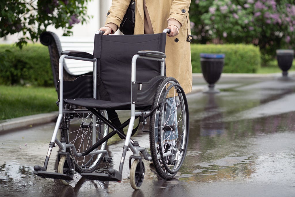 A person pushes an empty wheelchair.