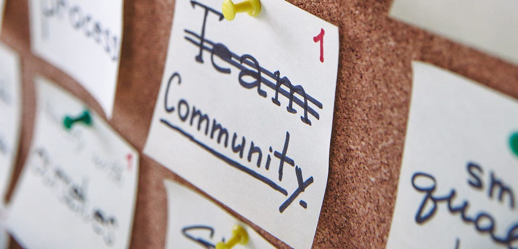 note cards pinned to cork board with “community” written on it