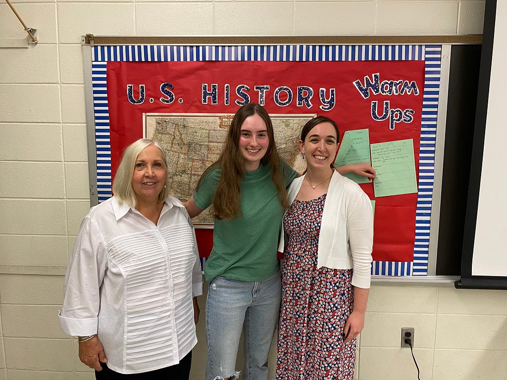 From left to right, Denise Sellers, president of the Haddon Fortnightly; Alexandra Himmel, president of the 50/50 Club; and Margaret Gammie, 50/50 Club advisor and social studies teacher and Haddonfield Memorial High. They stand in front of a red board with lettering. (photo courtesy of Claire Davenport)