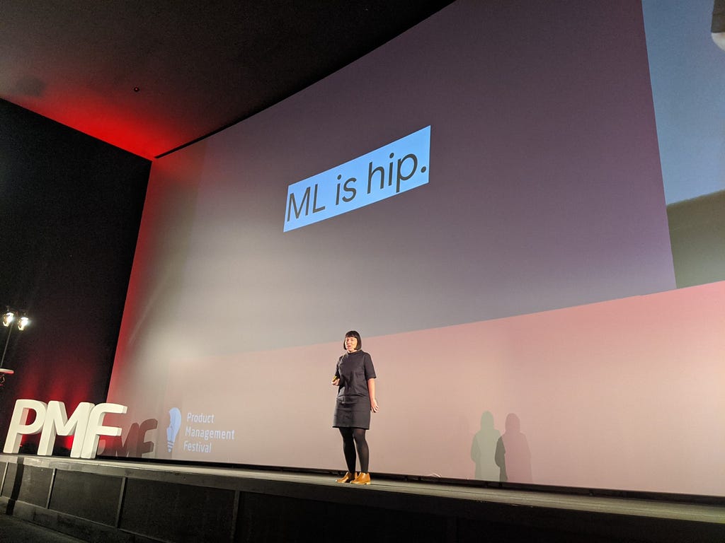 Photo of myself on stage at the conference. Slide text “ML is hip.”