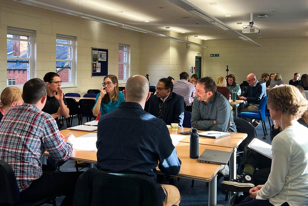 Professor Tim Heaton shares ideas for the Interdisciplinary Network on Time at their collaborative lab. The other two groups can also be seen sitting around tables in the background.