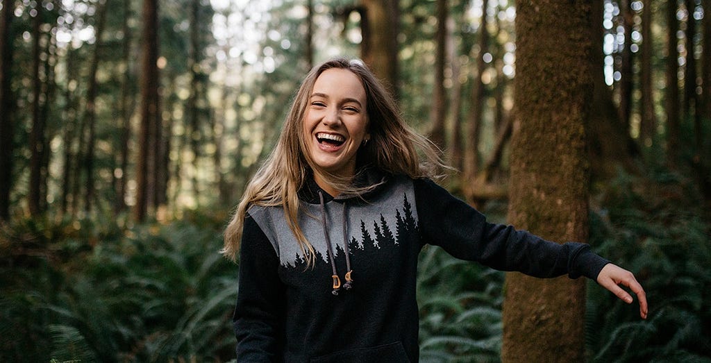 girl in the forest wearing tentree hoodie