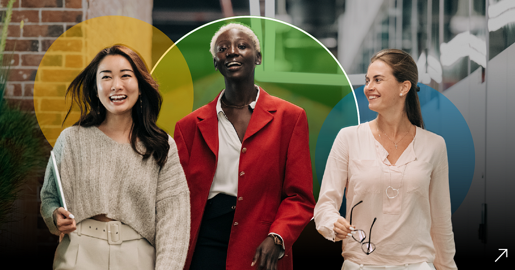 Front view of an asian woman, a black woman and a white woman walking side by side and smiling.