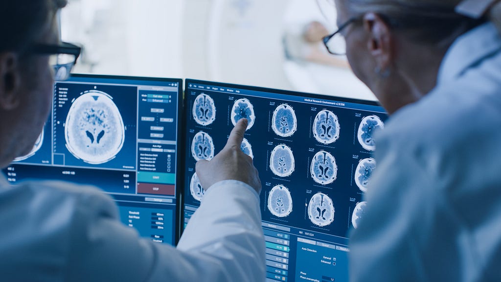 Imagem de dois médicos analisando exames do cérebro de um paciente.