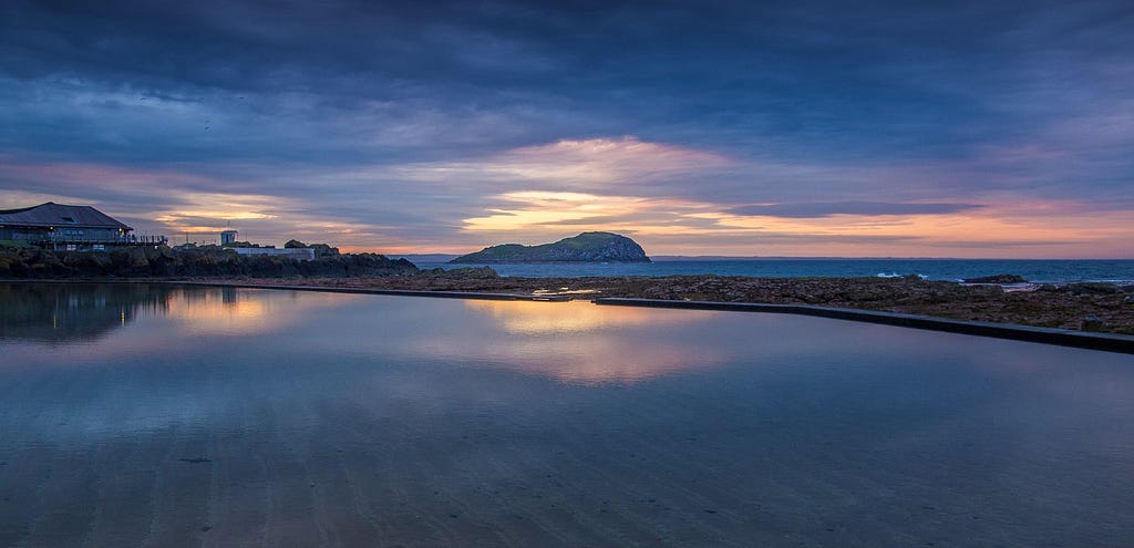 Sunset over a pool of water near North Berwick Harbour — it is evening — the day is changing to night
