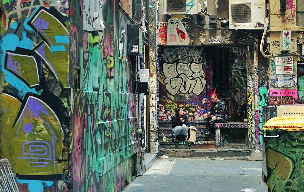 An alley covered with grafitti. A couple of punks hanging out.