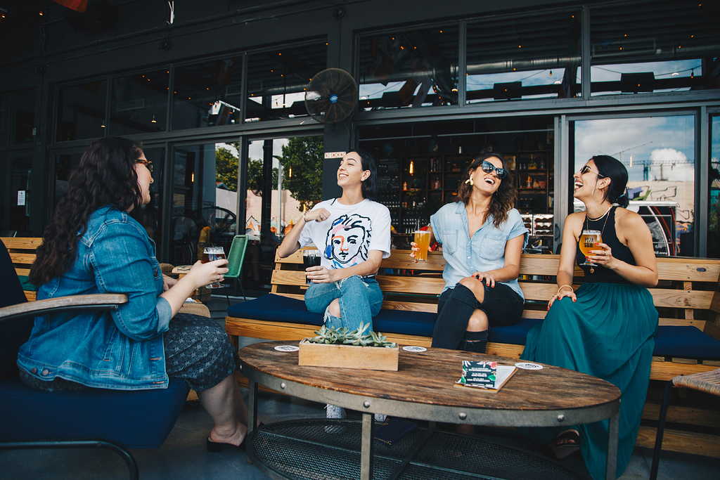 a group of friends sitting around a table drinking beer