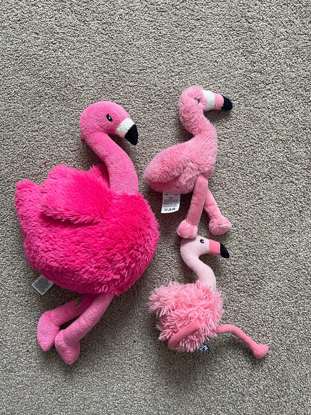 A trio of fluffy flamingo teddies, one large and two small