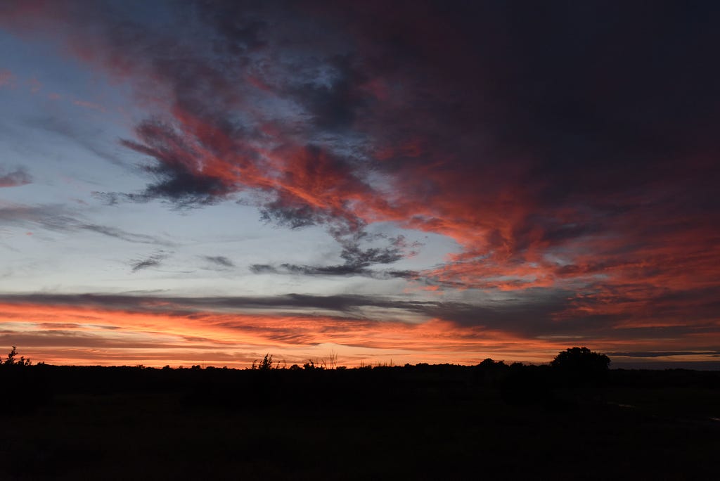 Landscape at sunset with orange, pink, and blue sky.