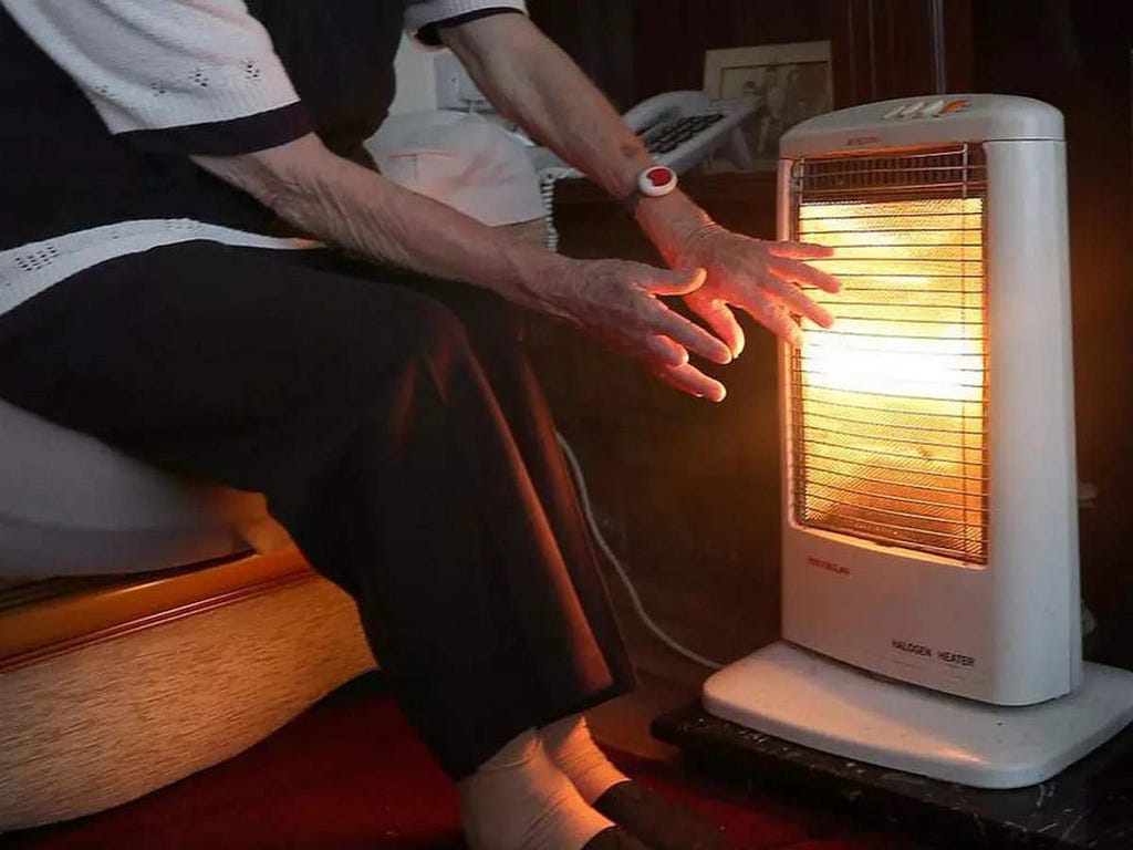 A man sitting in front of room heater.