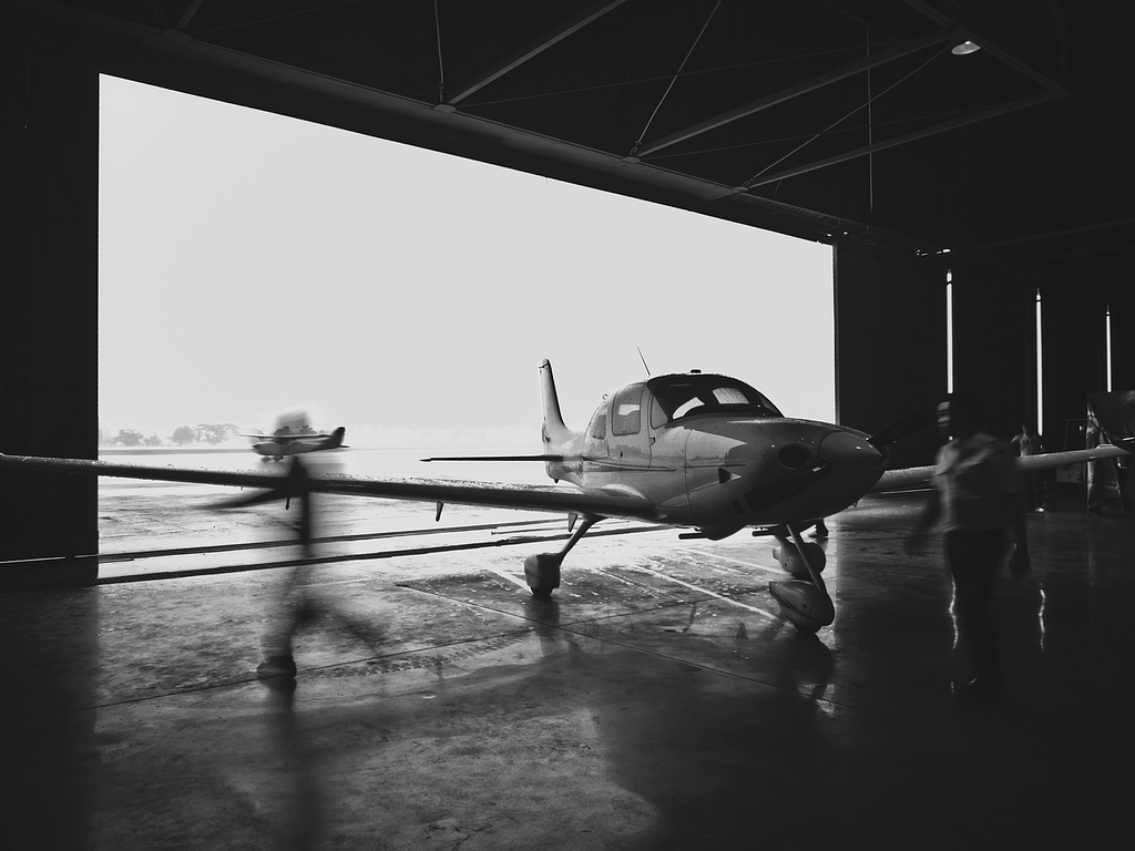 Black and white photo of a small airplane in a hangar.