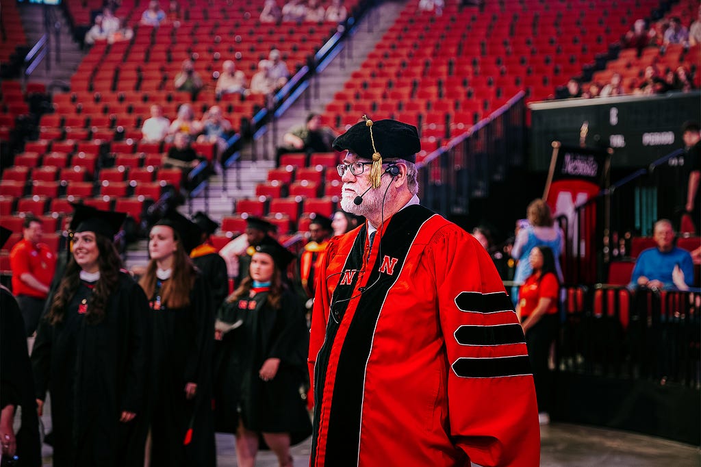 Bob Gorman observes as students begin making their way to their seats during graduate commencement