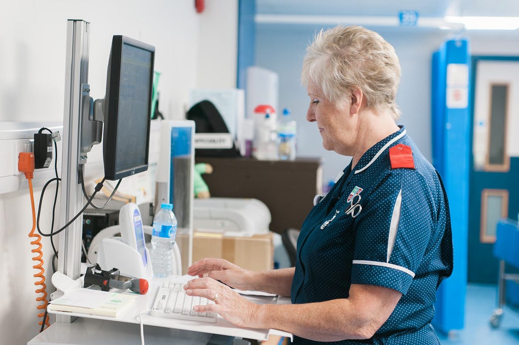 A picture of an NHS nurse at a computer screen in hospital.