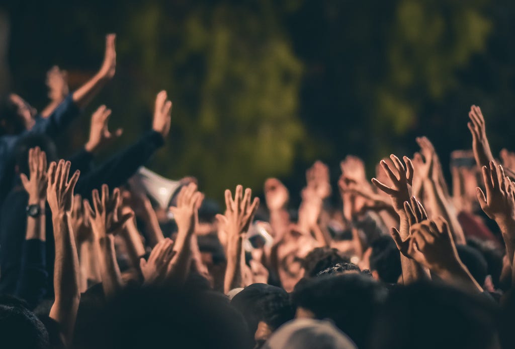 Photograph of a crowd of people with hands raised