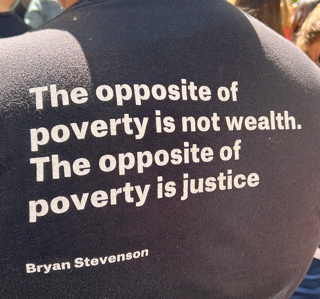 The back of shirt with the words, “The opposite of poverty is not wealth. The opposite of poverty is justice. Byron Stevenson”