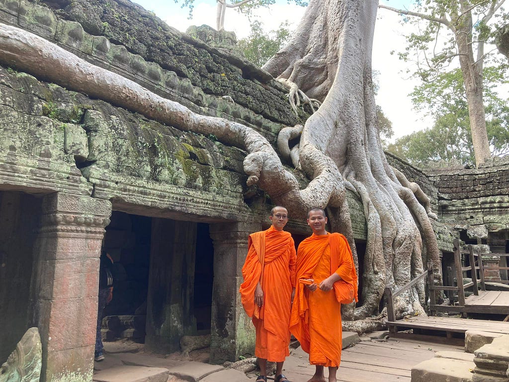 There are 2 monks. A big tree is growing on the temple.