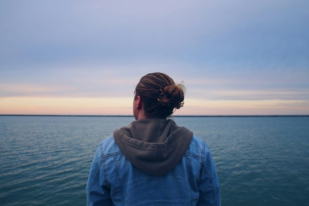 photo of the back of a person looking out into the ocean horizon