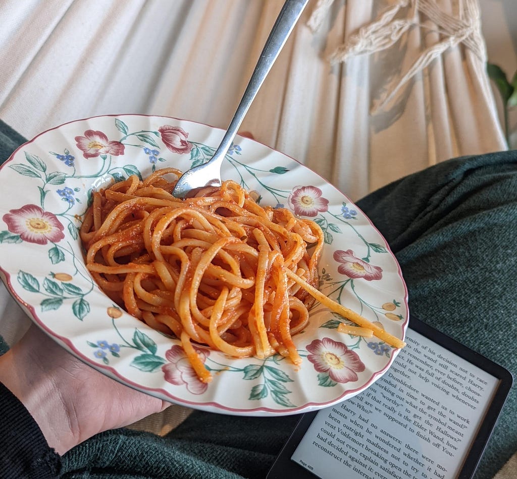 Myself holding a plate full of Amatriciana next to my kindle reader. The plate looks like an old fashion Nona plate with painted flowers, some would say ugly, I would say my favorite kind of plate.
