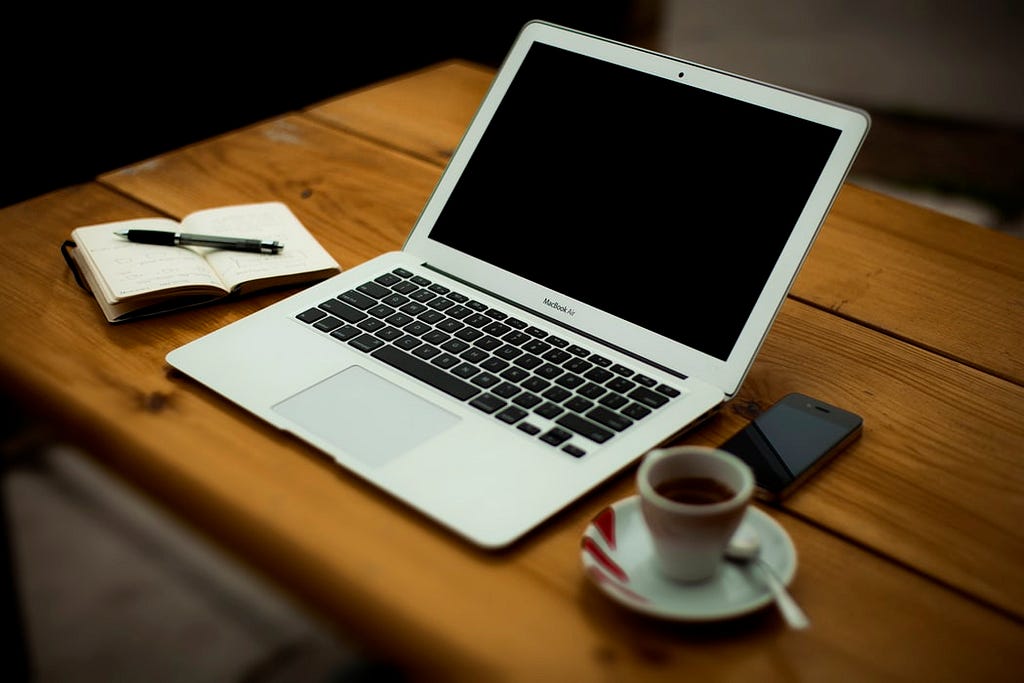 iphone, laptop, and pen on a table