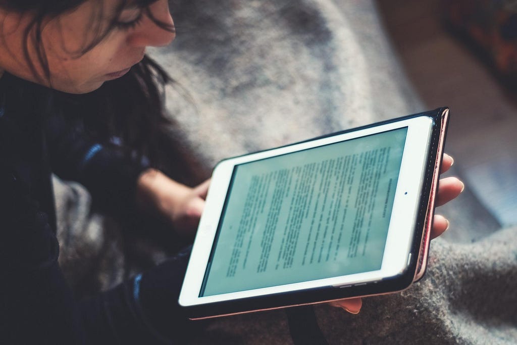 This image shows a person reading a document on a handheld tablet.