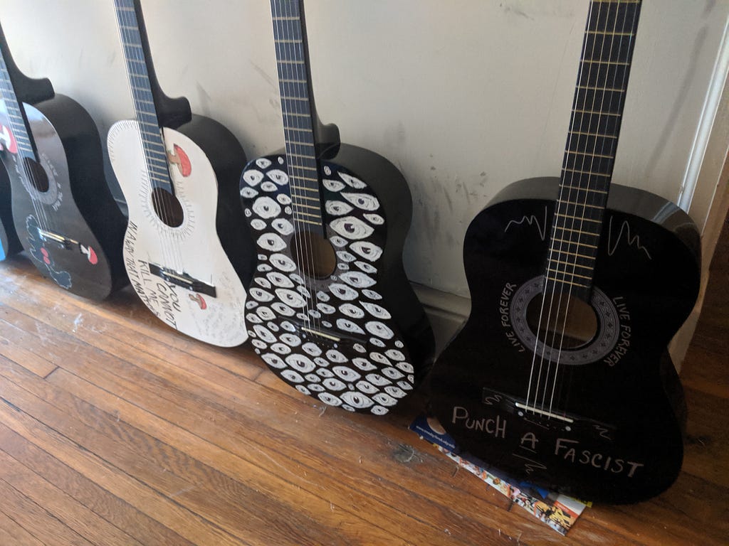 a collection of painted guitars lined up against a wall.