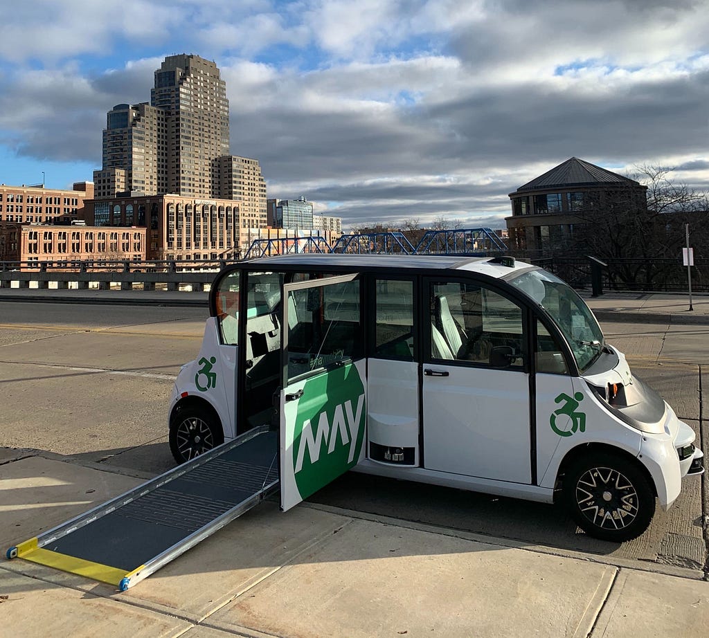 An autonomous May Mobility shuttle with a wheelchair ramp deployed at a stop in Grand Rapids, Michigan.