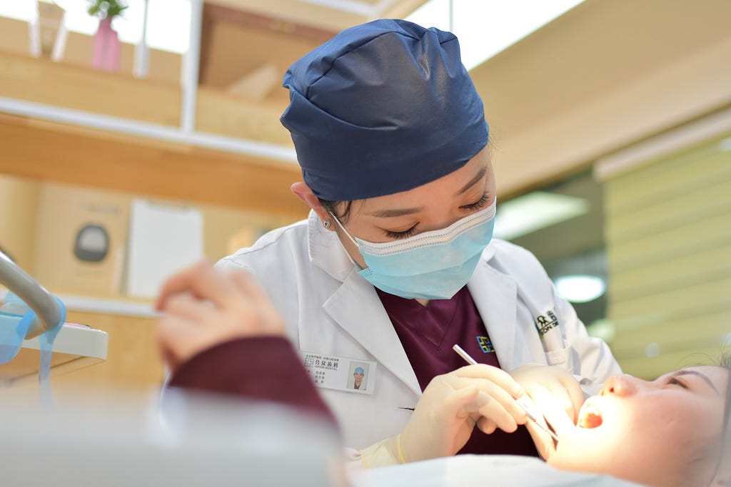 A dentist checks a patient’s teeth.