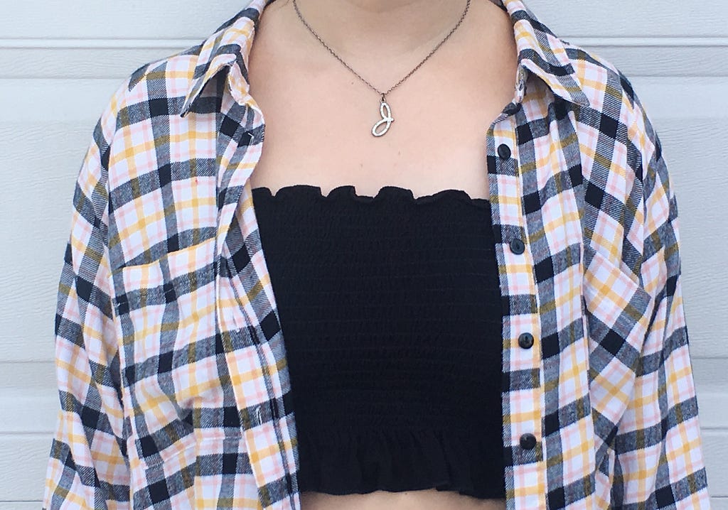 A black tube top underneath a black, yellow, and pink flannel.