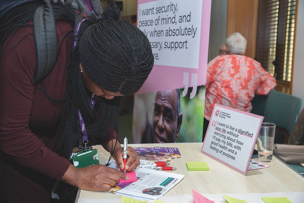 Woman writing on post it note at a stall as part of a campaigns event