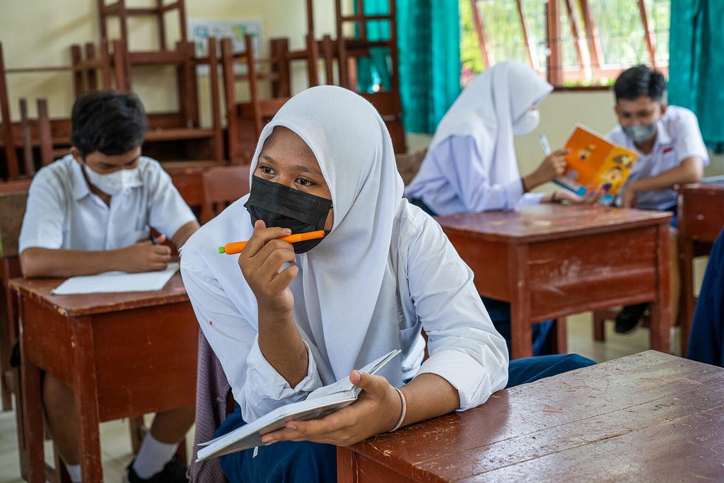 Four students wear masks and work in the notebooks