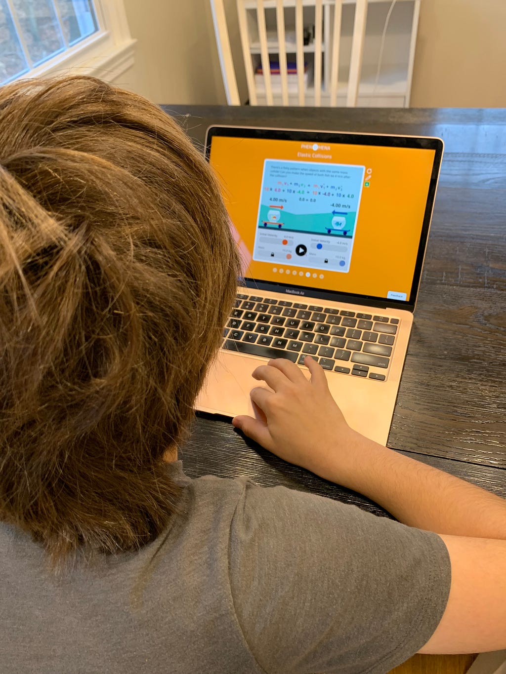 Image shows a child sitting in front of a laptop displaying a Phenomena experience.