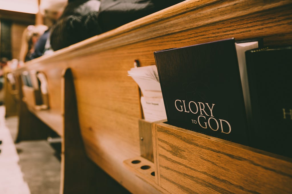 church pew with hymnal title “Glory to God”