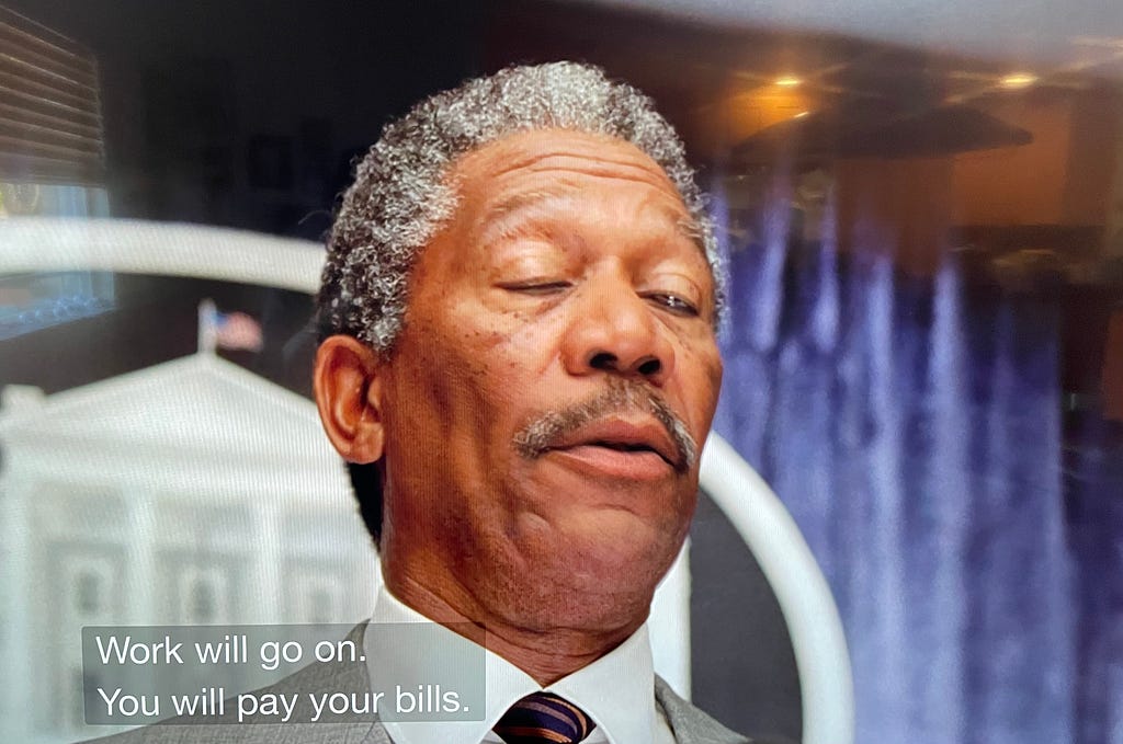 A super unflattering of Morgan Freeman as President Beck in Deep Impact, addressing the country on the news with the closed captions reading “Work will go on. You will pay your bills.”