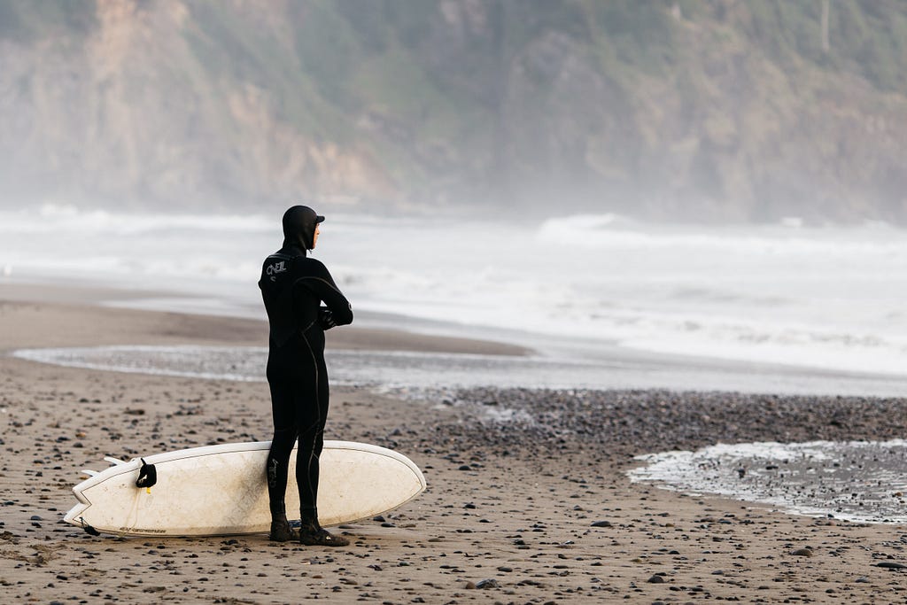Surfer in a wetsuit on the beach, thinking about going out into the ocean