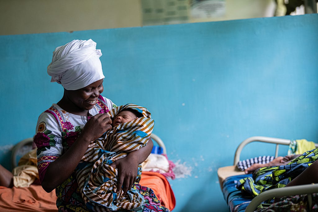 A smiling woman holds her newborn baby.