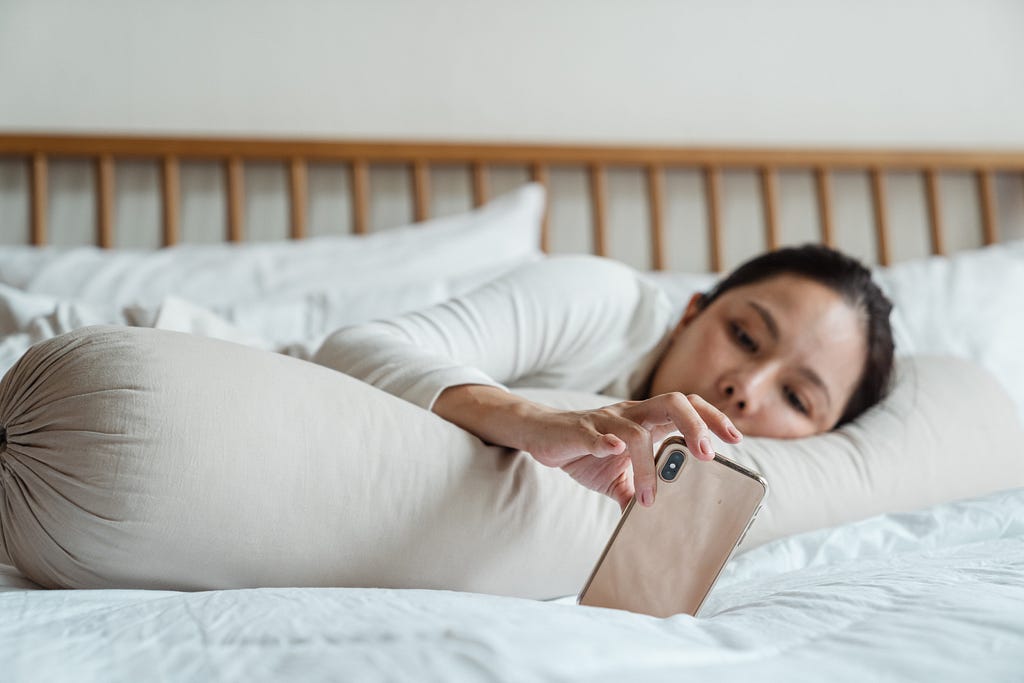 Woman looking at a smart phone in her bed