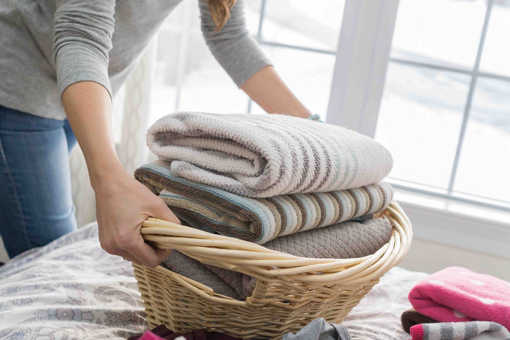 Person placing laundry basket on bed